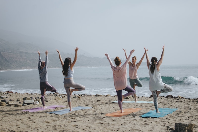 People doing yoga on the beach